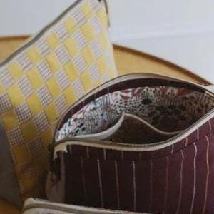 May include: A sewing pattern for a Plover Pouch, a fun and useful pouch in three sizes. The pattern includes instructions for sewing three different pouches with different fabric patterns. The text "Plover Pouch" and "noodlehead" are visible on the pattern.