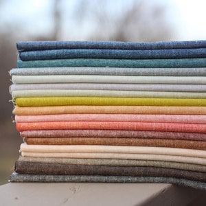 Peut inclure: Une pile de tissus pli&eacute;s de diff&eacute;rentes couleurs, dont le bleu, le vert, le jaune et le rose. Le tissu semble &ecirc;tre du lin ou une mati&egrave;re tiss&eacute;e similaire. La pile est bien rang&eacute;e, pr&eacute;sentant les diff&eacute;rentes teintes.