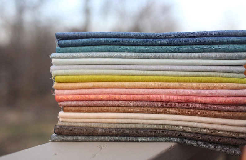 Peut inclure: Une pile de tissus pli&eacute;s de diff&eacute;rentes couleurs, dont le bleu, le vert, le jaune et le rose. Le tissu semble &ecirc;tre du lin ou une mati&egrave;re tiss&eacute;e similaire. La pile est bien rang&eacute;e, pr&eacute;sentant les diff&eacute;rentes teintes.
