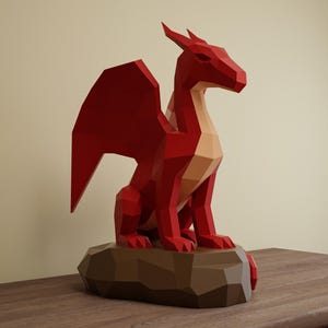 May include: A red geometric dragon sculpture with a tan underbelly and wings, perched on a brown, polygonal base. The dragon has a stylized, angular design, and is set against a neutral background.