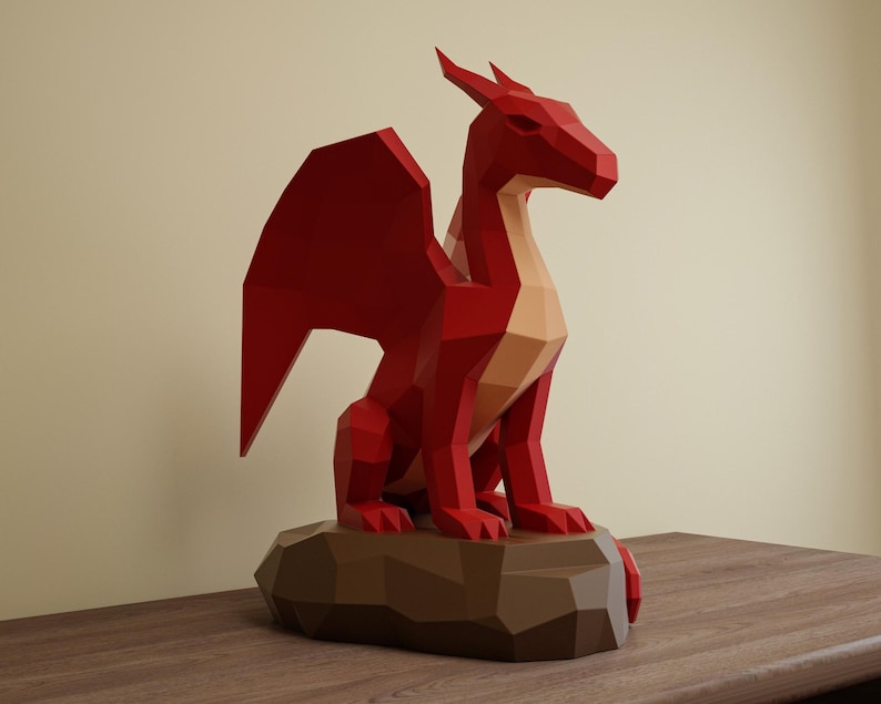 May include: A red geometric dragon sculpture with a tan underbelly and wings, perched on a brown, polygonal base. The dragon has a stylized, angular design, and is set against a neutral background.