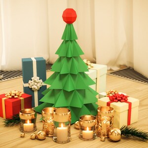 May include: A green paper origami Christmas tree with a red star on top, surrounded by wrapped gifts and gold candle holders with lit candles on a wooden surface.