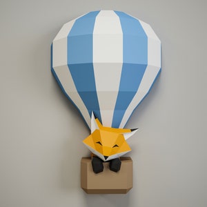 May include: A blue and white paper hot air balloon with a fox inside. The fox is orange and has black eyes and a black nose. The balloon is hanging from the ceiling.
