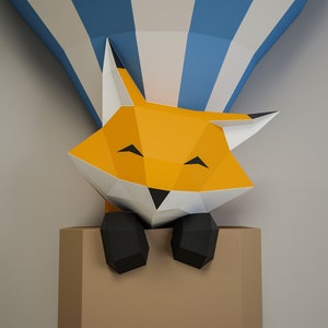 May include: A papercraft fox with orange fur, black eyes, and a black nose peeks out of a brown box. The fox is smiling and has its paws resting on the edge of the box. The fox is partially obscured by a blue and white striped hot air balloon.