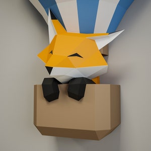 May include: A papercraft fox with orange fur and black eyes is sitting in a brown paper hot air balloon. The balloon has blue and white stripes.