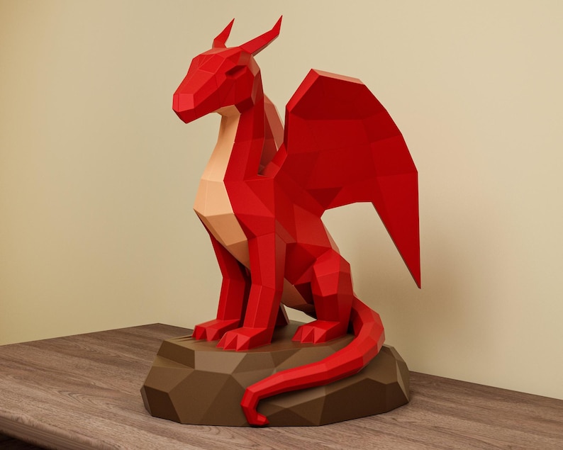 May include: A red geometric dragon sculpture with large wings, sitting on a brown, polygonal base. The dragon has a light tan chest and is posed with its tail curled. The sculpture is displayed on a wooden surface.