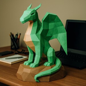 May include: A green paper dragon sculpture with geometric facets, sitting on a brown, faceted base. The dragon has outstretched wings and a tan chest. The sculpture is a decorative item, possibly for a desk or shelf.