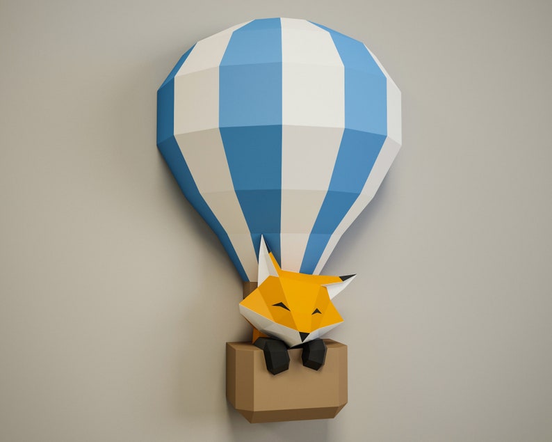 May include: A papercraft hot air balloon with blue and white stripes, with a fox inside the basket. The fox is orange with black eyes and a black nose.