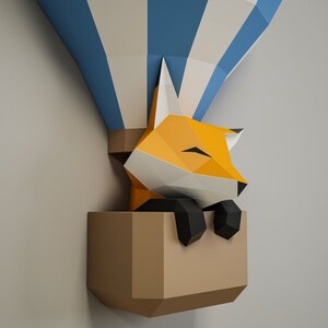 May include: A papercraft fox with orange fur and black eyes is sleeping inside a brown paper hot air balloon with blue and white stripes.