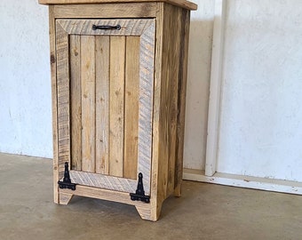 May include: A rustic wooden trash can with a single door and black metal hinges. The can is made of reclaimed wood and has a natural wood finish.