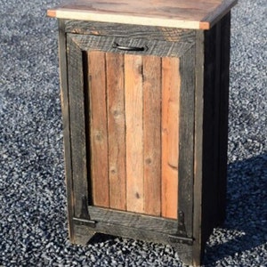 May include: A small wooden cabinet with a single door and a black metal handle. The cabinet is made of reclaimed wood with a dark stain and a natural wood top.