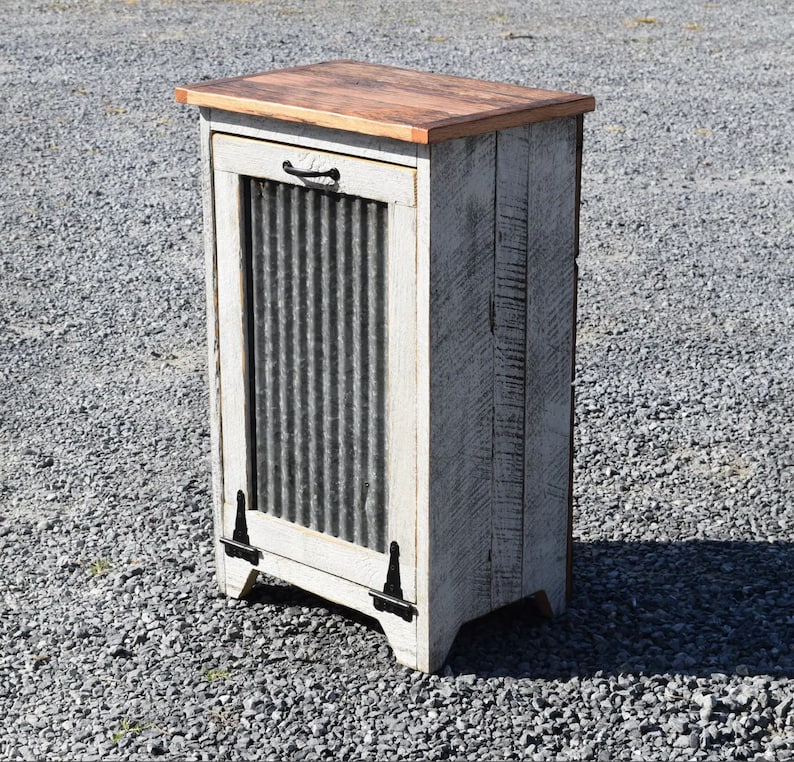 May include: White painted wooden cabinet with a corrugated metal door and a wood top. The cabinet has black hinges and a black handle.