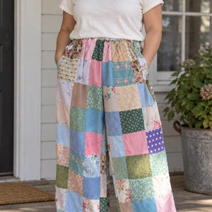 May include: A pair of wide-leg pants featuring a patchwork design made of various fabric squares in shades of pink, blue, green, and beige, with floral, polka dot, and solid patterns, an elasticized waistband, and side pockets.
