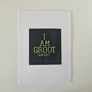 May include: A white card with a black square in the center. The square has green text that reads "I AM GROOT - GROOT".