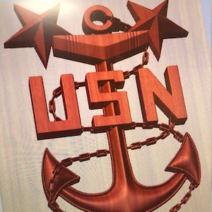 Peut inclure: Une ancre en métal rouge avec une chaîne enroulée autour. Deux étoiles rouges sont au sommet de l'ancre, et les lettres "USN" sont au centre de l'ancre.