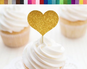 Op de afbeelding: Gouden glitter hart cupcake topper. De topper zit op een cupcake met witte frosting. De cupcake staat op een witte kant. De tekst "RSUP PARTY DECOR" staat in de rechter benedenhoek van de afbeelding.
