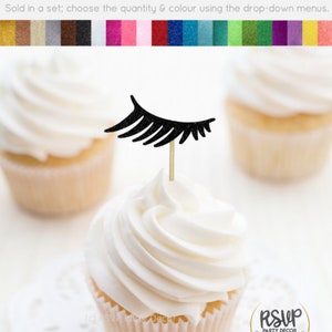 May include: Black glitter eyelash cupcake topper on a white cupcake. The cupcake topper is on a gold toothpick. The cupcake is on a white doily. The background is white. The text "RSVP Party Decor" is on a gold circle with a green and white banner.