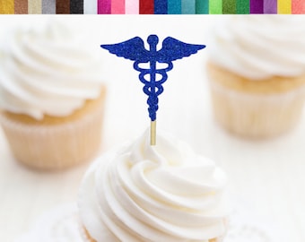 May include: Blue glitter cupcake topper with a medical caduceus symbol. The topper is on a white cupcake with white frosting. The cupcake is on a white doily. The text "RSVP Party Decor" is on a gold circle with a teal border.