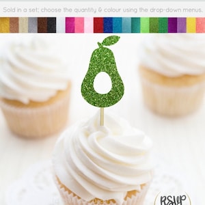 Puede incluir: Topper de cupcake de aguacate verde con purpurina y una hoja. El topper está en un cupcake blanco con glaseado blanco. El cupcake está en un encaje blanco. El texto "RSVP Party Decor" está en un círculo dorado.