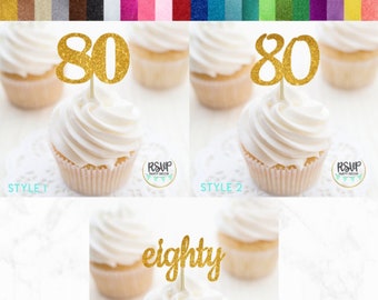 May include: Three cupcake toppers with gold glitter accents. The first two toppers feature the number 80, the third topper says "eighty".