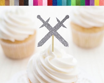 May include: Silver glitter crossed swords cupcake toppers. The swords are made of cardstock and are attached to a wooden stick. The toppers are perfect for a birthday party or any other special occasion.