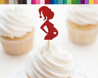 Könnte beinhalten: Roter Glitzer-Karton-Cupcake-Topper in Form einer schwangeren Person mit Weihnachtsmütze. Der Topper befindet sich auf einem Holzstab und ist auf einem Cupcake mit weißem Zuckerguss platziert. Das Bild zeigt auch andere Cupcakes und den Text "Cupcake Toppers/Food Picks - Glitter Cardstock".