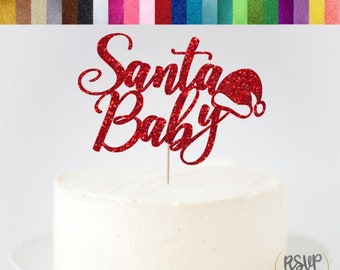 Könnte beinhalten: Ein roter Glitzer-Karton-Kuchenaufsatz mit dem Schriftzug "Santa Baby" in Schreibschrift und einem Weihnachtsmützen-Design. Der Aufsatz befindet sich auf einem weiß glasierten Kuchen. Eine Farbkarte mit verfügbaren Glitzerkartonfarben ist ebenfalls zu sehen.
