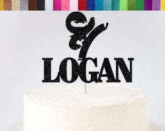 May include: Black glitter cardstock cake topper featuring a silhouette of a ninja kicking with the name Logan written below.