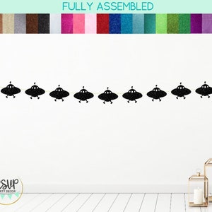 May include: Black glitter UFO party banner with the text "RSVP Party Decor" on a white wall.