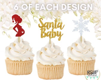 Könnte beinhalten: Cupcakes mit dekorativen Aufsätzen. Ein Cupcake hat einen roten Glitzer-Schwangeren-Aufsatz, ein anderer einen goldenen Glitzer-"Santa Baby"-Aufsatz und der letzte einen silbernen Glitzer-Schneeflocken-Aufsatz. Der Text "6 OF EACH DESIGN" ist enthalten.
