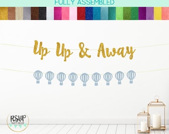 Puede incluir: Pancarta de purpurina dorada con el texto "Up Up & Away" y una hilera de globos aerostáticos de purpurina azul claro.