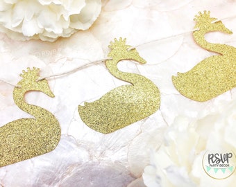 May include: Gold glitter swan banner with a crown on each swan. The banner is strung on twine and is perfect for a princess-themed party.