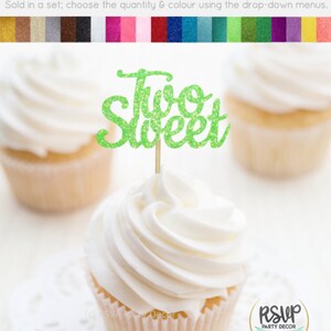 May include: Green glitter cupcake topper with the text "Two Sweet" on a white cupcake with white frosting.
