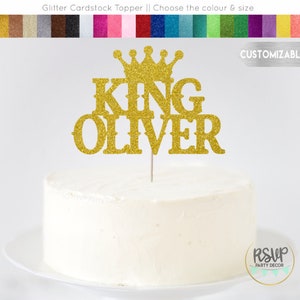 May include: Gold glitter cardstock cake topper with a crown and the words "KING OLIVER".