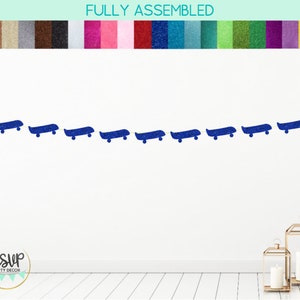 Op de afbeelding: Een blauwe glitter skateboard banner met de tekst "RSVP Party Decor" op een witte muur achtergrond.