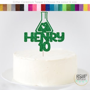 Könnte beinhalten: Grüner Glitzer-Kuchentopper aus Karton mit einem Becherglas, dem Namen Henry und der Zahl 10.