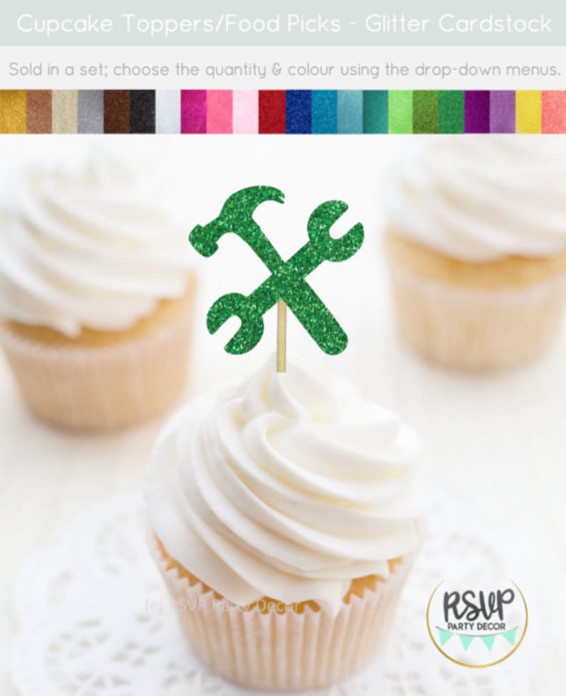 May include: Green glitter cupcake topper with a hammer and wrench design. The topper is on a white cupcake with white frosting.
