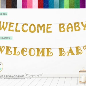 May include: Gold glitter welcome baby banner with two different font styles. The banner is pre-strung and ready to hang. The banner is shown hanging on a white wall with a wooden floor.