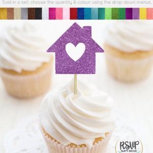 May include: Purple glitter cupcake topper shaped like a house with a white heart in the center. The topper is on a cupcake with white frosting. The text "RSUP PARTY DECOR" is visible in the bottom right corner of the image.