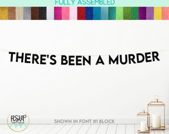 May include: Black glitter banner with the text "THERE'S BEEN A MURDER" hanging on a white wall. The banner is fully assembled and ready to hang.