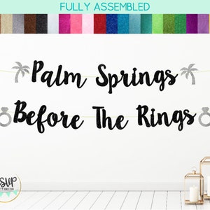 May include: Black glitter banner with the text "Palm Springs Before The Rings" with silver glitter palm trees and ring icons.