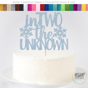 May include: Blue glitter cardstock cake topper with the text "InTWO the UNKNOWN" and two snowflakes.