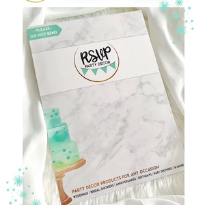May include: A white envelope with a marble pattern and the text "HAPPY MAIL" in a teal green font. The envelope has a gold circle with the text "RSUP PARTY DECOR" in black text. The envelope is decorated with a teal green cake with gold stars and a gold stand. The text "PARTY DECOR PRODUCTS FOR ANY OCCASION" is printed in brown text. The text "WEDDINGS | BRIDAL SHOWERS | ANNIVERSARIES | BIRTHDAYS | BABY SHOWERS & MORE" is printed in brown text. The text "SECURELY PACKAGED IN A FESTIVE HARDSHELL MAILER" is printed in black text.