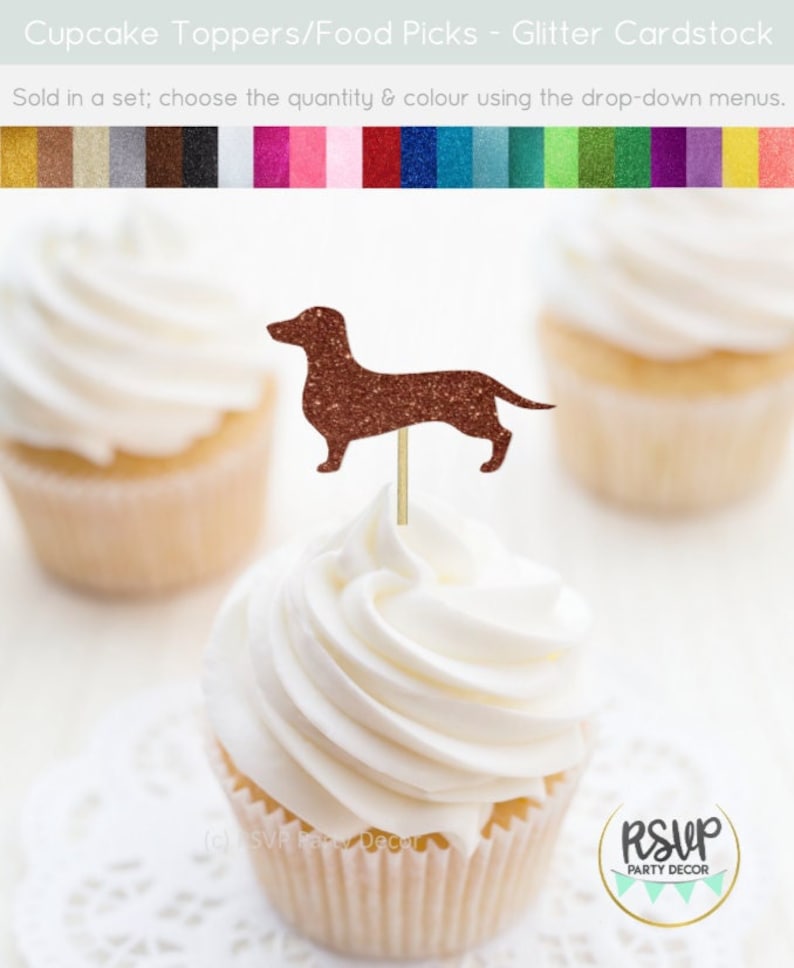 May include: A cupcake topped with a brown glitter dachshund cupcake topper. The cupcake topper is on a wooden stick. The cupcake is on a white doily. The text "RSVP Party Decor" is on the bottom right of the image.