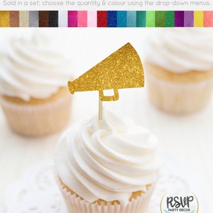 May include: A gold glitter cardstock megaphone cupcake topper on a cupcake with white frosting. The image shows three cupcakes, with the focus on the front cupcake. The text at the top says "Cupcake Toppers/Food Picks - Glitter Cardstock".