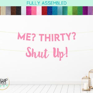 Puede incluir: Pancarta de brillo rosa con el texto "ME? THIRTY? Shut Up!" colgada en una pared blanca.