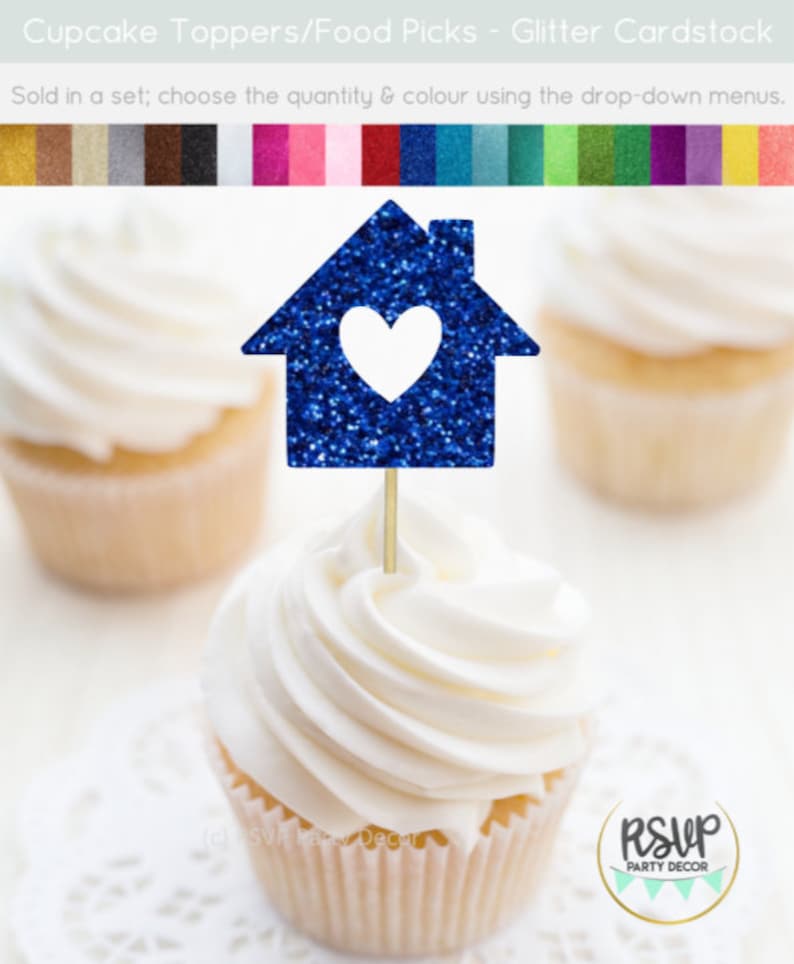 May include: Blue glitter cupcake topper shaped like a house with a white heart inside. The topper is on a wooden stick and is perfect for a housewarming party or a new home celebration.