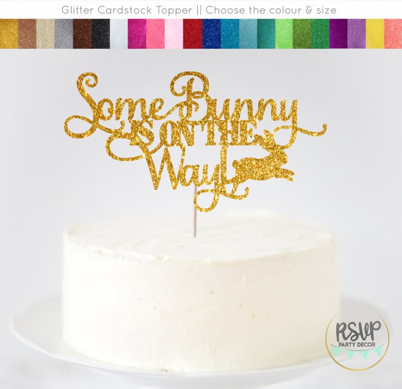 May include: Gold glitter cardstock cake topper with the text "Some Bunny is on the Way" and a bunny silhouette.
