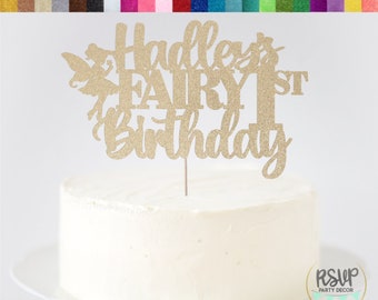 May include: Gold glitter cardstock cake topper with the text "Hadley's Fairy 1st Birthday" and a fairy silhouette.