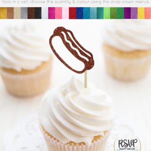 May include: A cupcake with white frosting and a glittery brown hot dog food pick. Two other cupcakes with white frosting are also visible. The image includes the text "Cupcake Toppers/Food Picks - Glitter Cardstock". The RSVP Party Decor logo is in the bottom right.